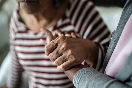 cuidador sosteniendo la mano de una mujer mayor como apoyo