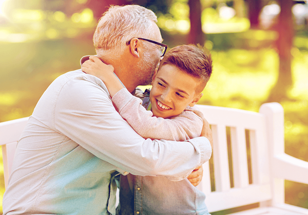 grandfather and grandson hugging at park